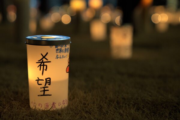 夜空を彩る追悼の花火　地上ではキャンドルが想いを灯す